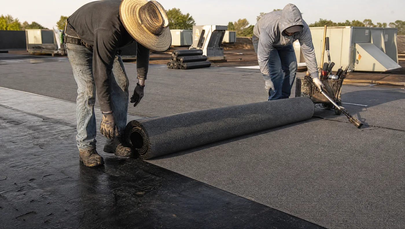 Torch-applied modified bitumen cap sheet being rolled out on a Houston roof